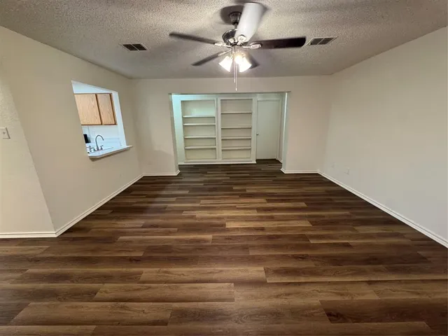 a view of empty room with window and ceiling fan