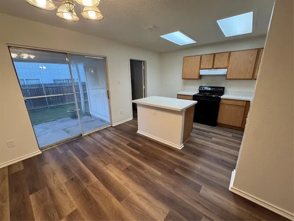 a kitchen view with wooden floor and electronic appliances