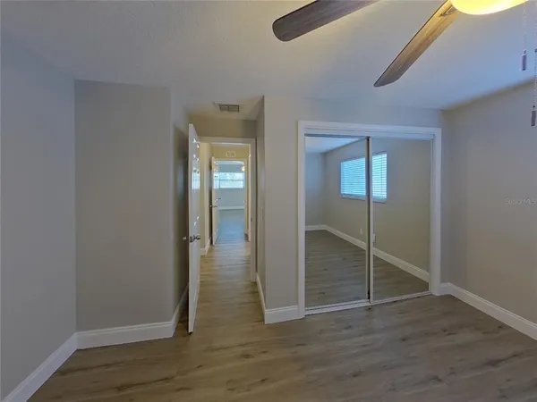 an empty room with wooden floor mirror and windows
