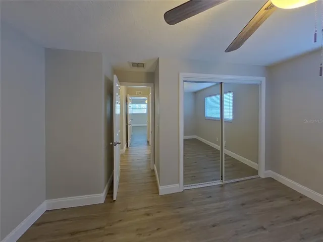 an empty room with wooden floor mirror and windows