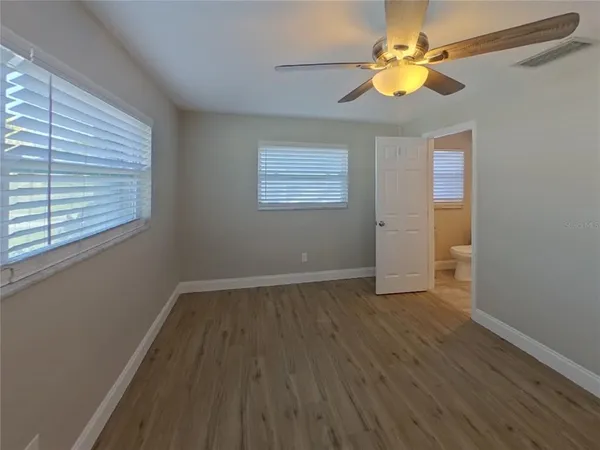 a view of an empty room with window and wooden floor