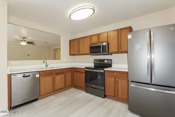 a kitchen with stainless steel appliances granite countertop a stove a sink dishwasher a refrigerator and a microwave oven with wooden floor