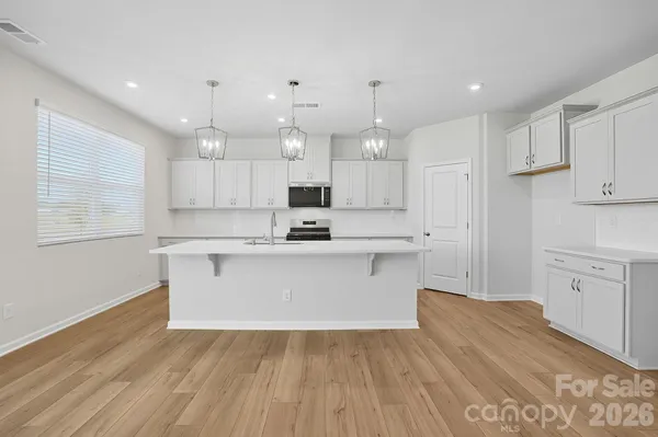 a large white kitchen with kitchen island a sink white cabinets and white appliances