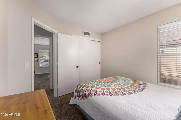 a bed sitting in a bedroom next to a bathroom with a sink and a mirror