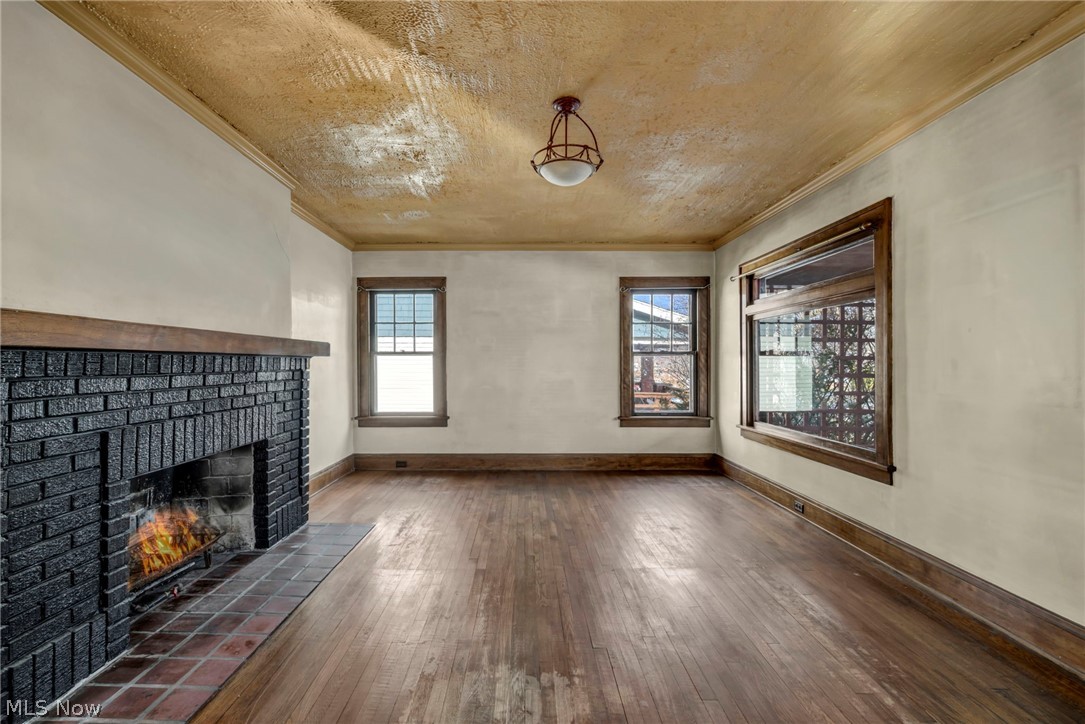 3272 Tullamore Road Cleveland, OH 44118 - Photo 9 of 47 Unfurnished living room featuring dark wood-style floors, a fireplace, and ornamental molding