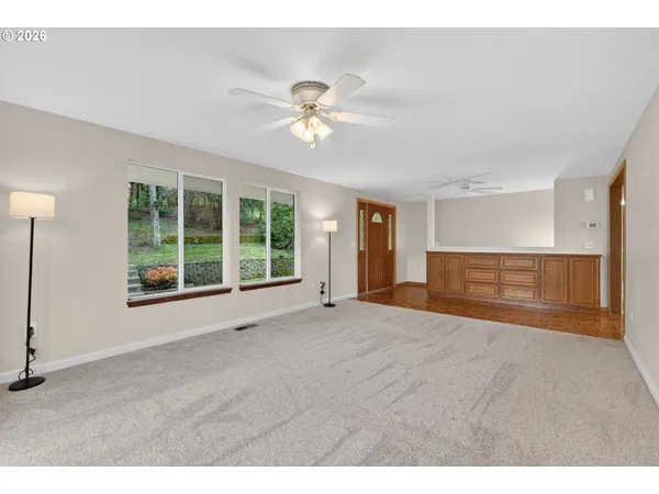 a view of an empty room with a window and kitchen view