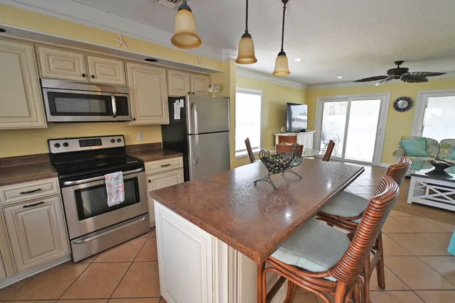 a kitchen with stainless steel appliances granite countertop a stove a refrigerator a kitchen island a table and chairs