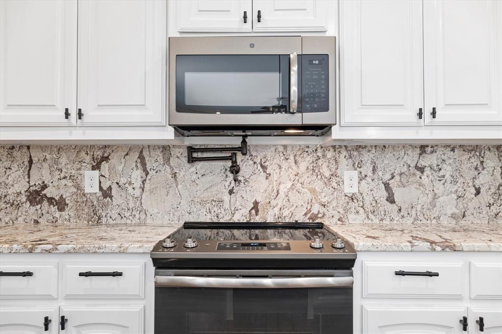 3511 West J E Woody Road Springtown, TX 76082 - Photo 13 of 34 Kitchen featuring stainless steel appliances, white cabinetry, light stone countertops, and tasteful backsplash