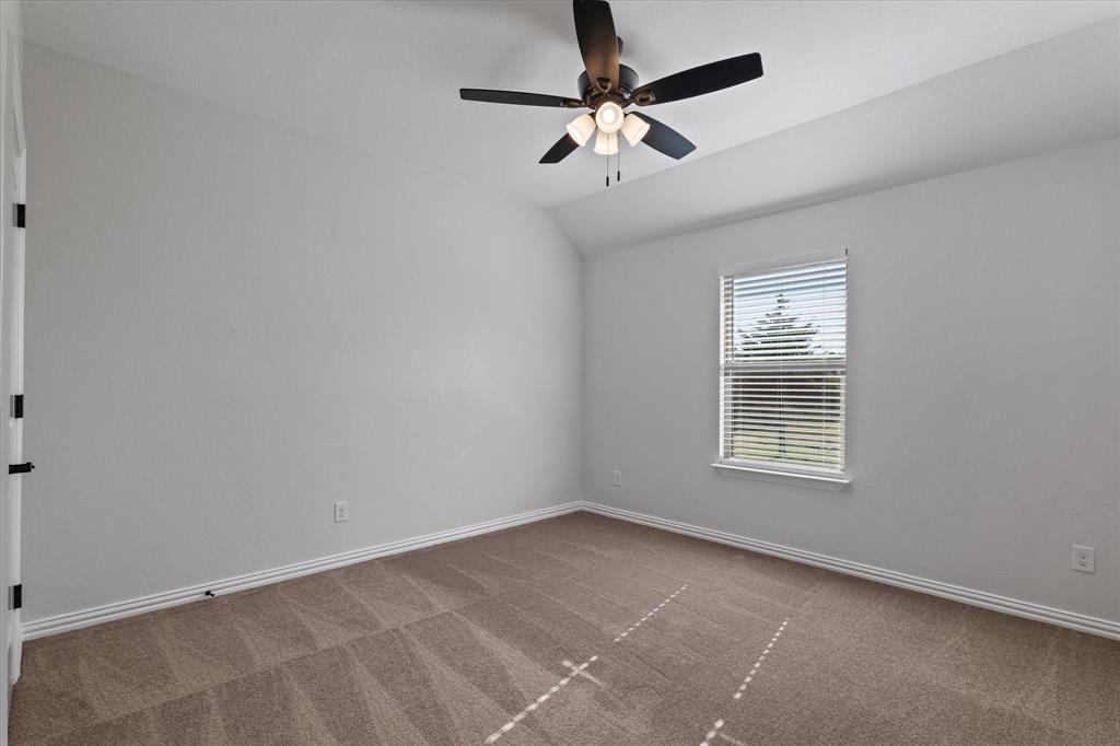 3511 West J E Woody Road Springtown, TX 76082 - Photo 25 of 34 Spare room featuring carpet floors, vaulted ceiling, and a ceiling fan