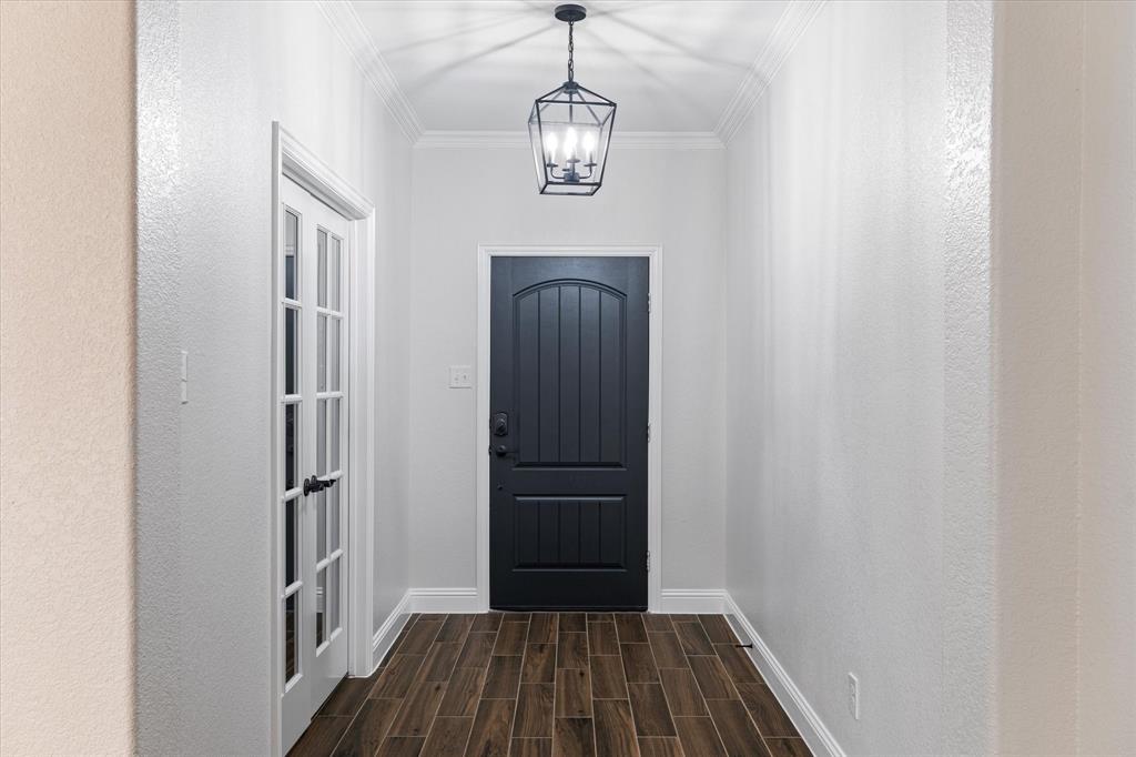 3511 West J E Woody Road Springtown, TX 76082 - Photo 4 of 34 Doorway to outside featuring wood finish floors, ornamental molding, and a chandelier