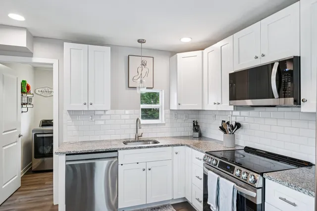 a kitchen with granite countertop white cabinets and black appliances