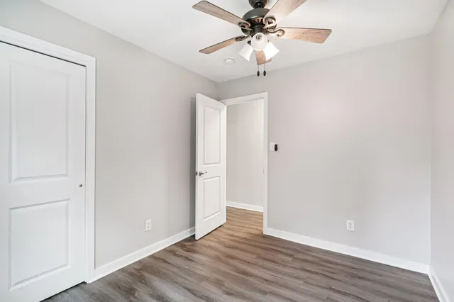 an empty room with wooden floor fan and windows
