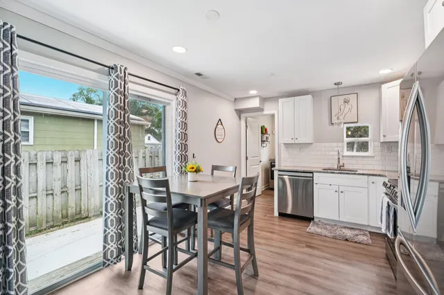 a kitchen with stainless steel appliances a dining table chairs and wooden floor