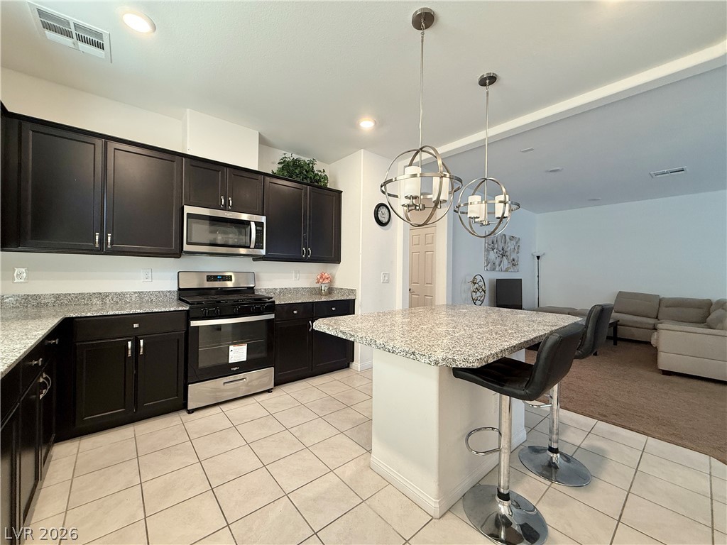 7777 South Westwind Road Las Vegas, NV 89139 - Photo 28 of 46 A well-appointed kitchen features dark cabinetry, durable countertops, and an inviting island with pendant lighting.