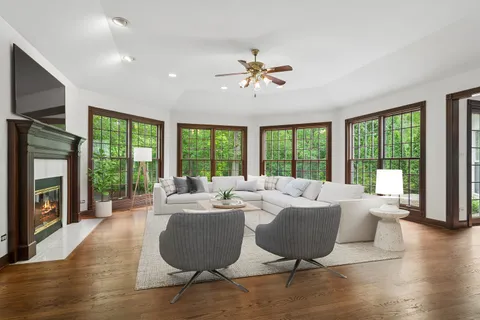 a living room with furniture floor to ceiling window hardwood floor and a flat screen tv