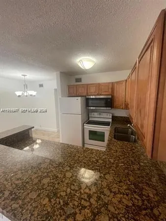a kitchen with kitchen island granite countertop a refrigerator and a sink