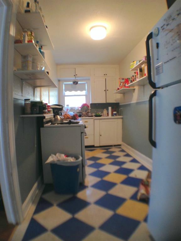Kitchen featuring open shelves, white appliances, white cabinets, dark flooring, and light countertops