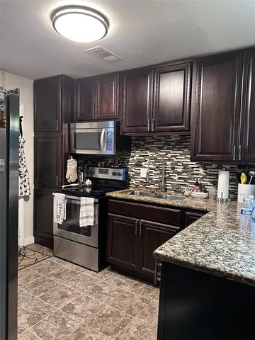 a kitchen with granite countertop stainless steel appliances and wooden cabinets