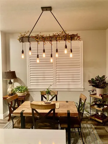 a kitchen with stainless steel appliances granite countertop a stove a sink a refrigerator white cabinets and chairs with wooden floor