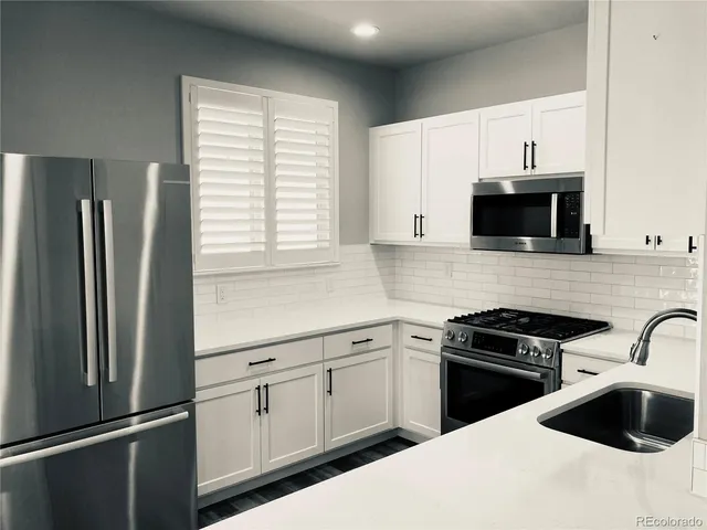 a kitchen with white cabinets and black appliances