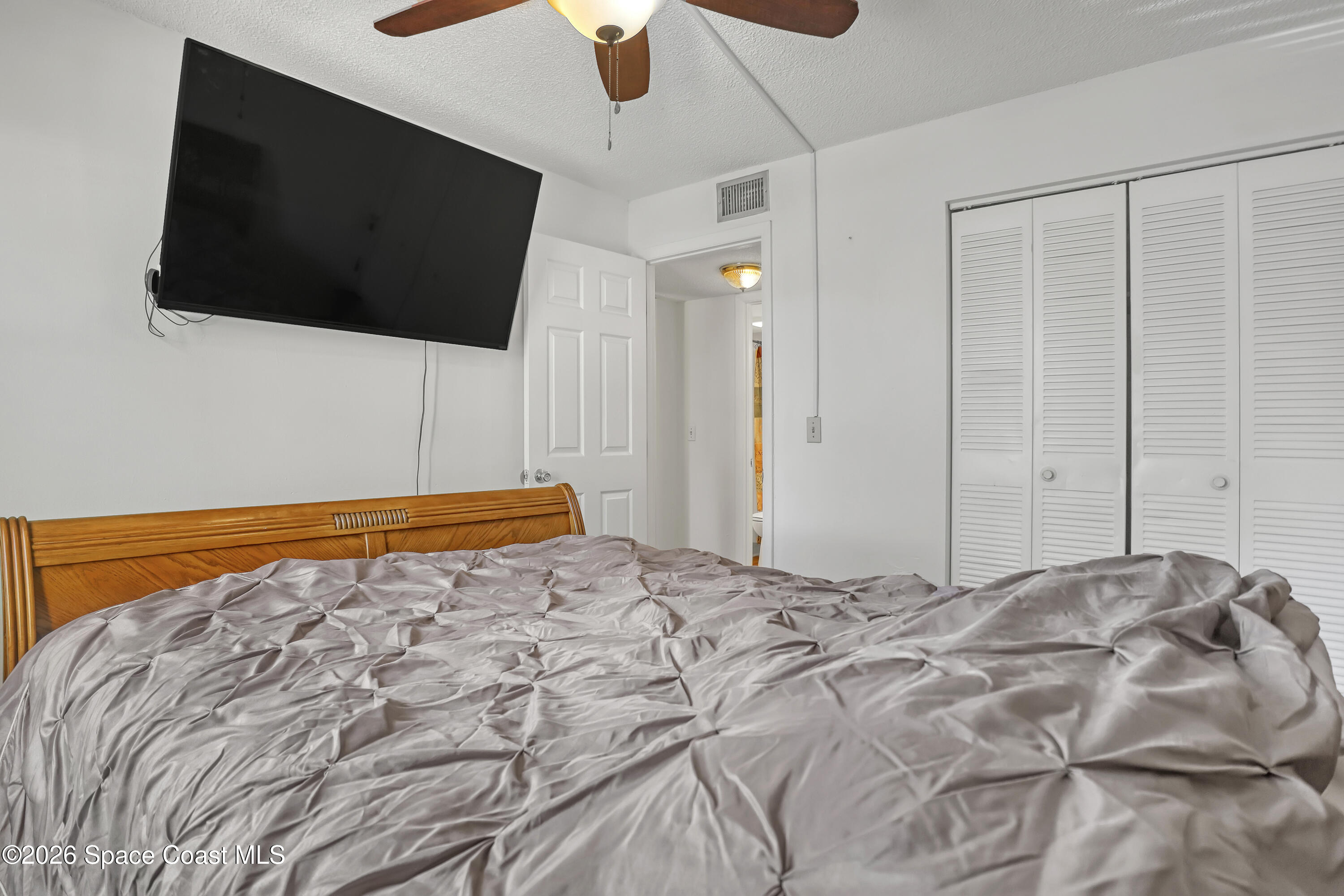 588 North Wickham Road, Unit 51 Melbourne, FL 32935 - Photo 17 of 27 a bedroom with a bed and a flat screen tv