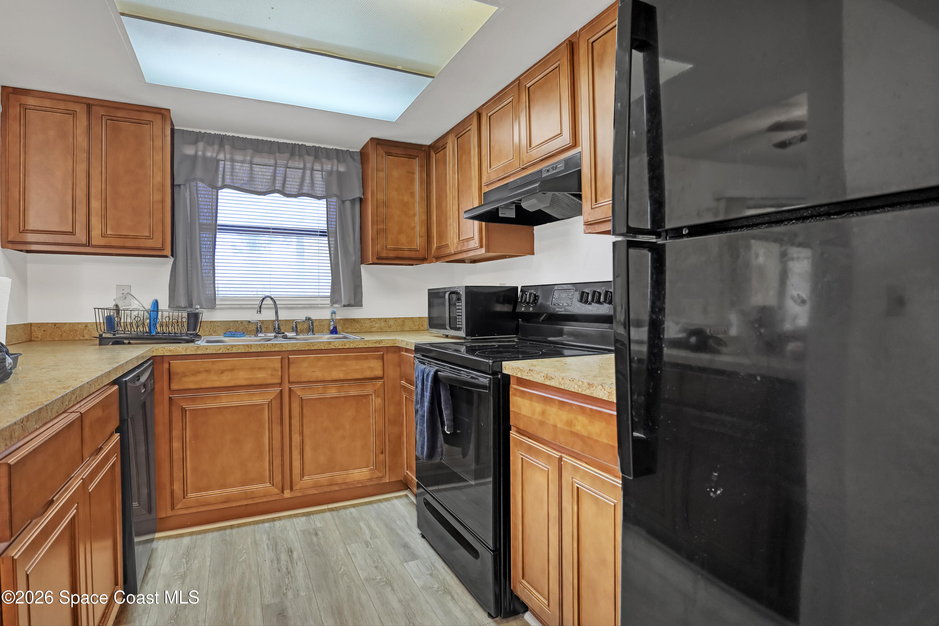 588 North Wickham Road, Unit 51 Melbourne, FL 32935 - Photo 9 of 27 a kitchen with stainless steel appliances granite countertop a refrigerator a sink dishwasher and wooden cabinets with wooden floor