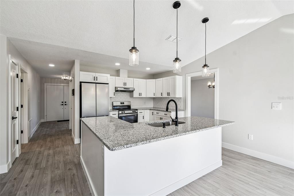 5248 Frost Road Spring Hill, FL 34606 - Photo 29 of 70 a kitchen with stainless steel appliances granite countertop a sink a refrigerator a stove and a wooden floor
