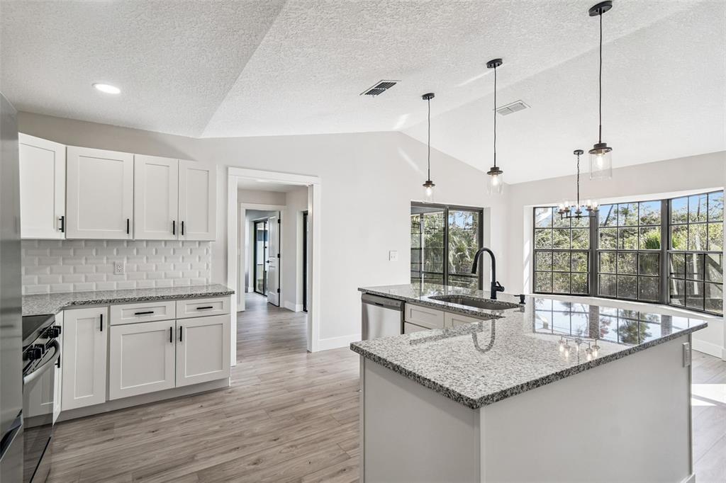 5248 Frost Road Spring Hill, FL 34606 - Photo 32 of 70 a kitchen with stainless steel appliances granite countertop a sink a center island and wooden floor