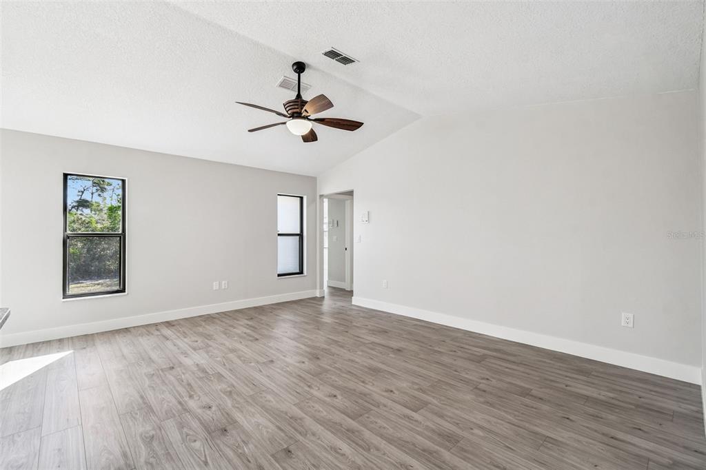 5248 Frost Road Spring Hill, FL 34606 - Photo 41 of 70 an empty room with wooden floor chandelier fan and windows