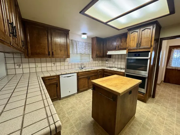a kitchen with stainless steel appliances granite countertop a stove a sink dishwasher and a refrigerator