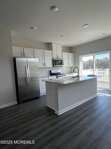 a kitchen with stainless steel appliances granite countertop a refrigerator a stove top oven a sink and dishwasher with wooden floor