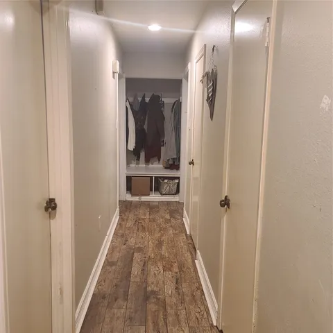 a view of a hallway with wooden floor and a bathroom