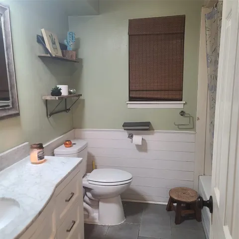 a bathroom with a granite countertop toilet sink and mirror