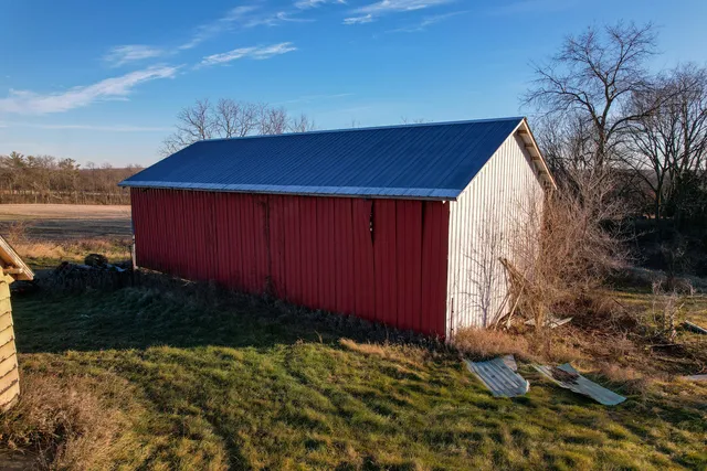 a backyard of a house with wooden table and chairs