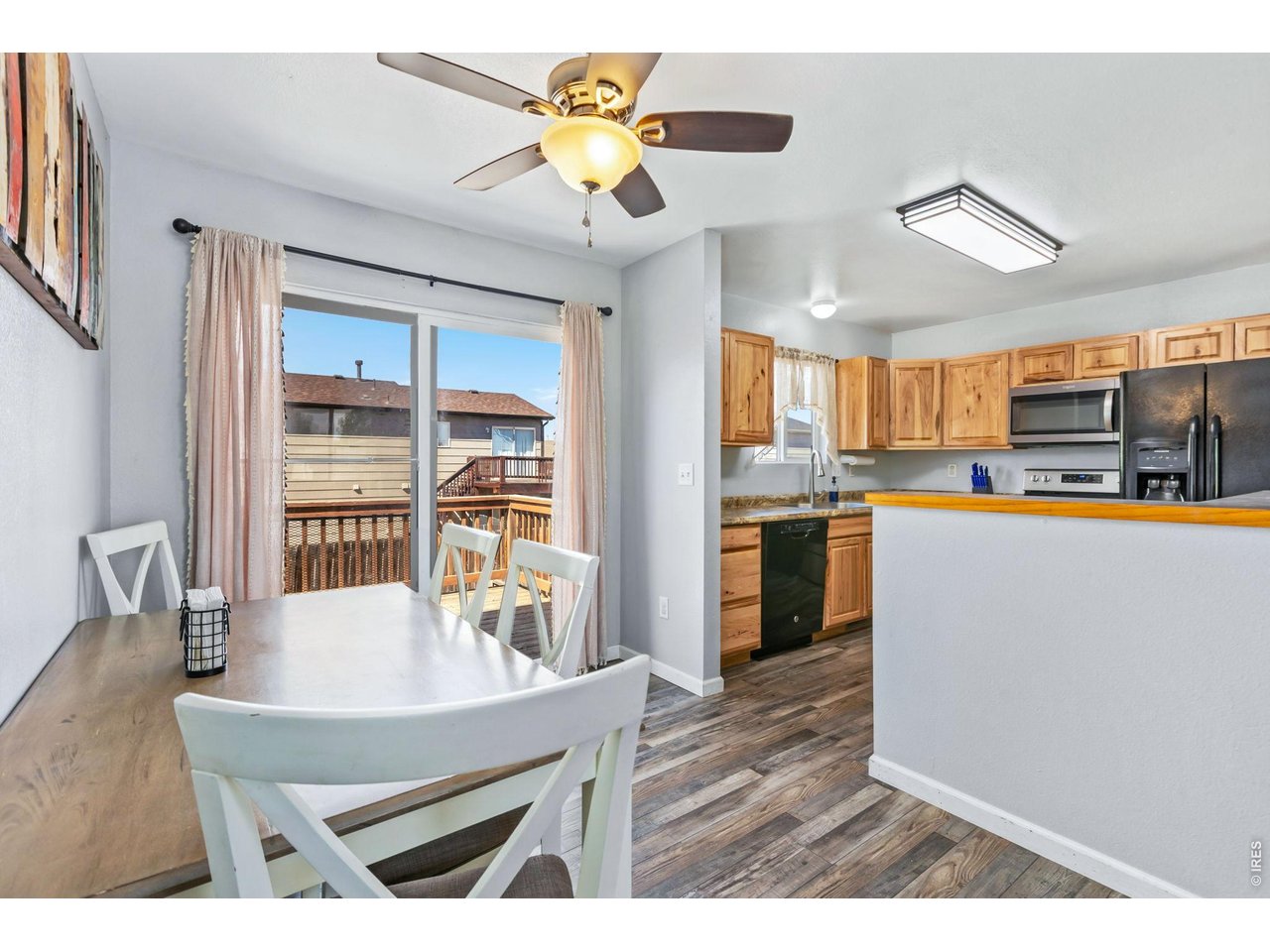 233 East 19th Street Road Greeley, CO 80631 - Photo 7 of 22 a kitchen with stainless steel appliances granite countertop a refrigerator a stove top oven a dining table and chairs with wooden floor