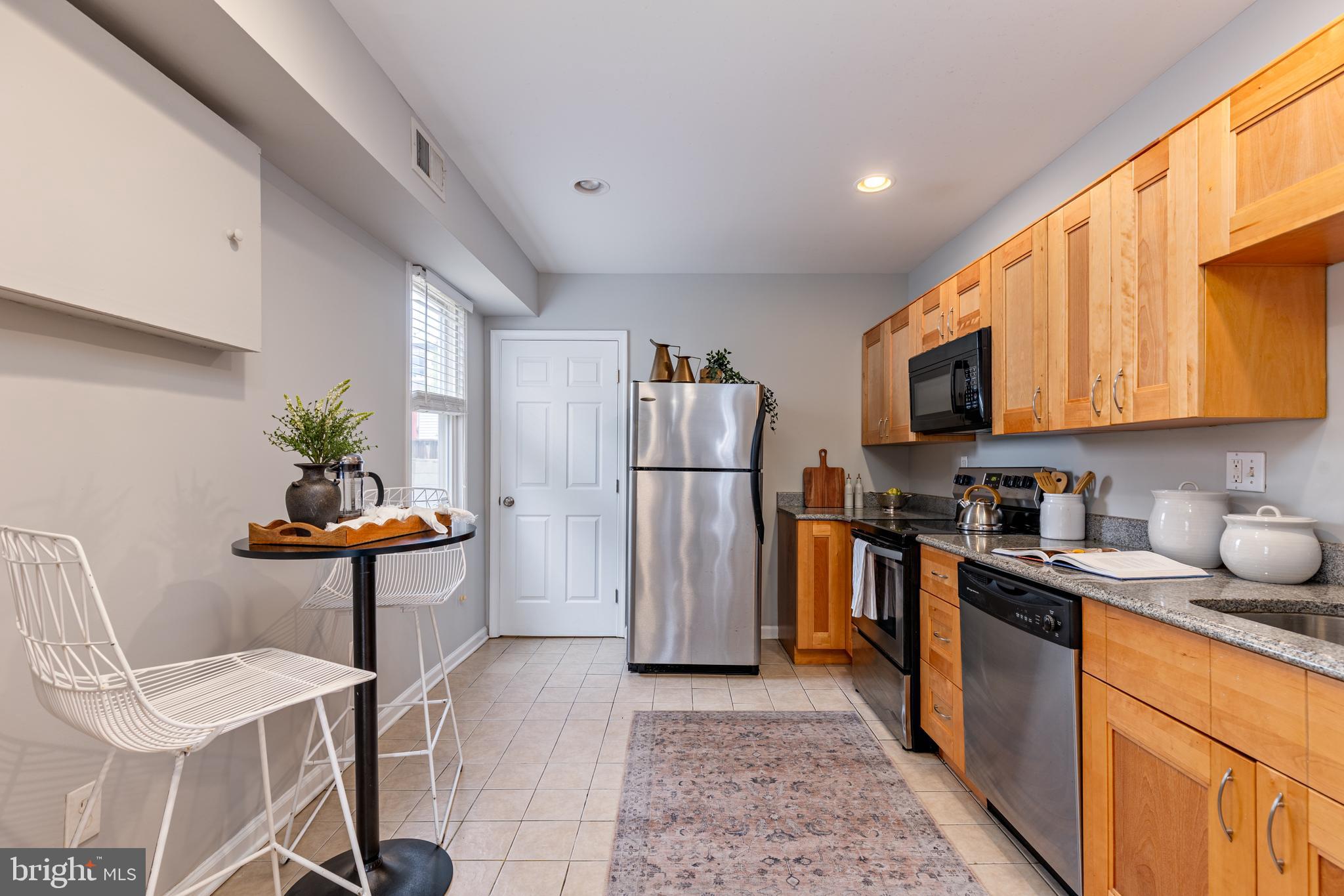 305 South Castle Street Baltimore, MD 21231 - Photo 5 of 28 a kitchen with stainless steel appliances granite countertop a refrigerator a stove a sink a dining table and chairs with wooden floor