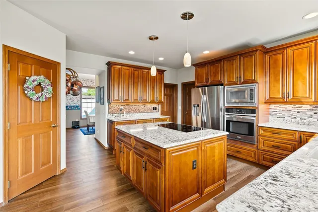 a kitchen with stainless steel appliances granite countertop a refrigerator a stove and a wooden cabinets