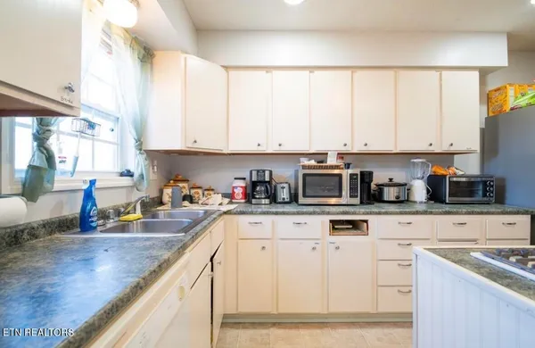 a kitchen with stainless steel appliances granite countertop a stove a sink and white cabinets