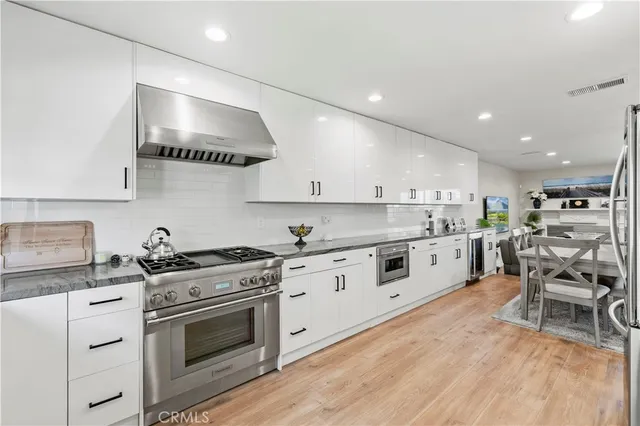 a kitchen with stainless steel appliances a stove a sink and white cabinets