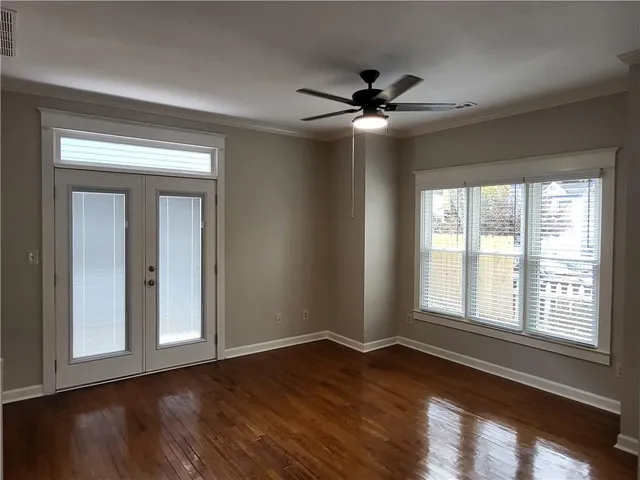 a view of an empty room with wooden floor and a window