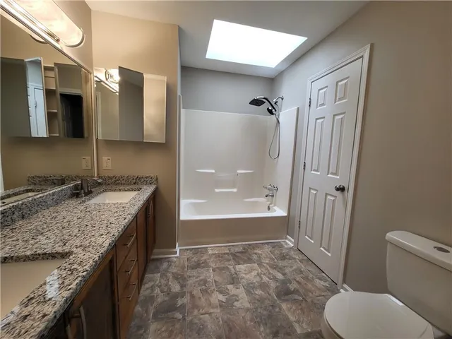 a bathroom with a granite countertop sink toilet and shower