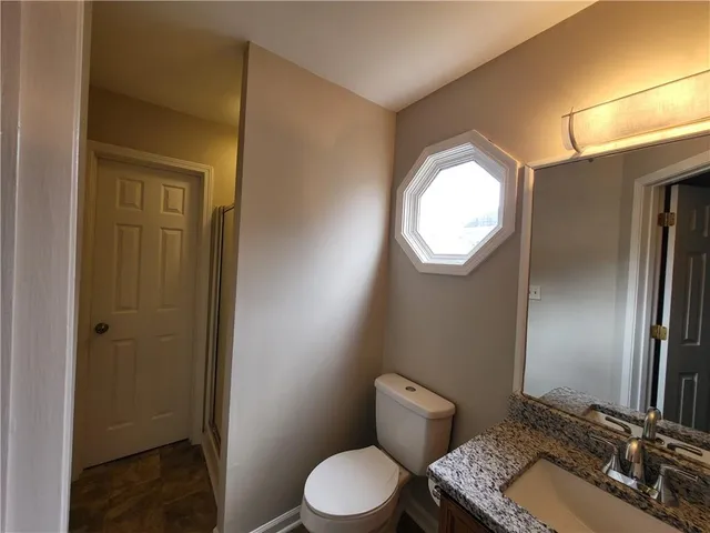 a bathroom with a granite countertop toilet sink and mirror