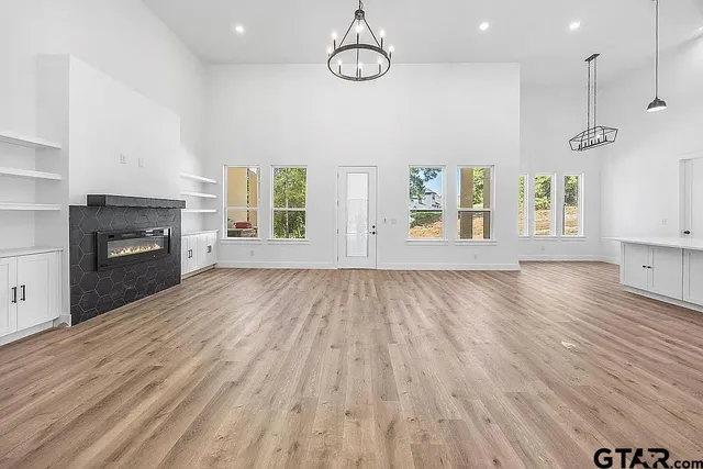 an empty room with wooden floor fireplace and windows