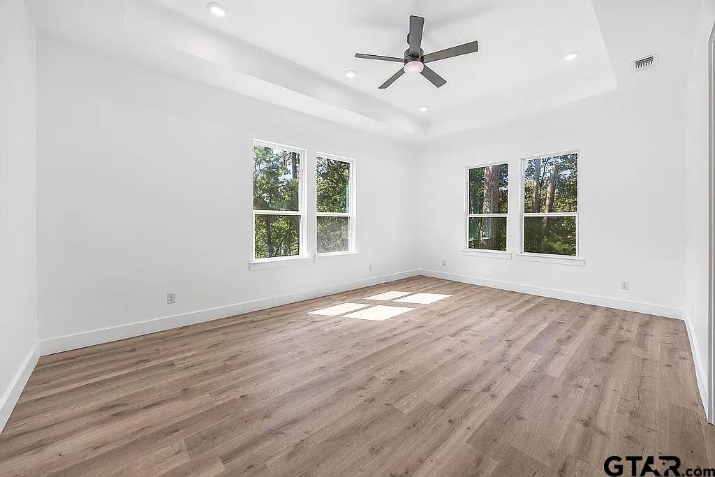 4504 Triggs Trace Tyler, TX 75709 - Photo 31 of 46 an empty room with wooden floor ceiling fan and windows