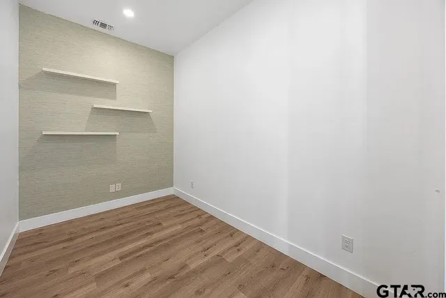 a view of an empty room with wooden floor