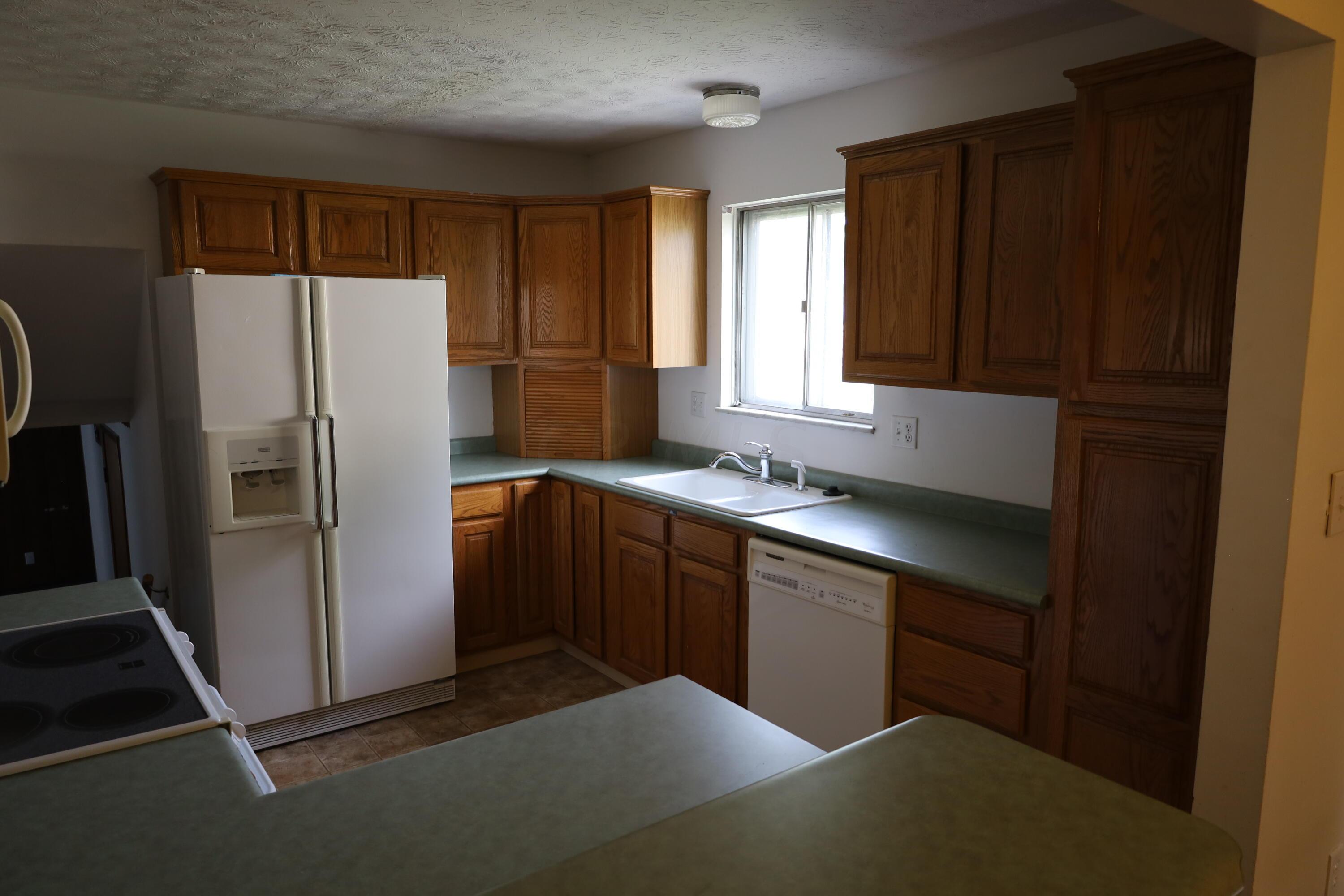 3864 Edendale Road Columbus, OH 43207 - Photo 8 of 24 11'7" x 9'11" - Roper Refrigerator, Frigidaire Electric Stove, Whirpool Dishwasher, Sharp Microwave, white porcelain sink with double bowl, wood grain cabinets, aqua laminate countertops, light taupe ceramic tile, white painted walls