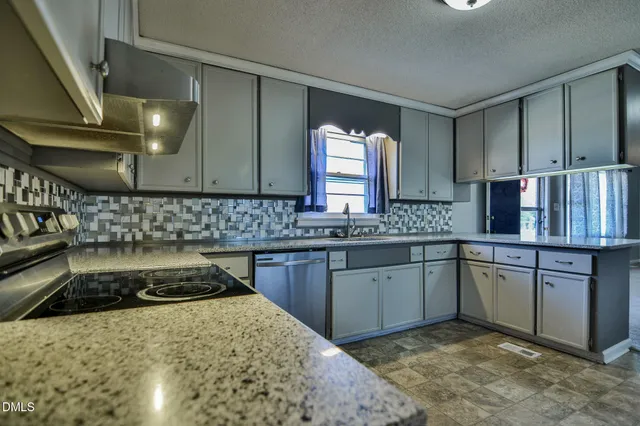 a kitchen with granite countertop white cabinets and stainless steel appliances