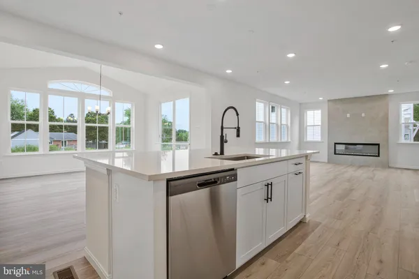 a view of a kitchen with a sink stainless steel appliances wooden floor and a window