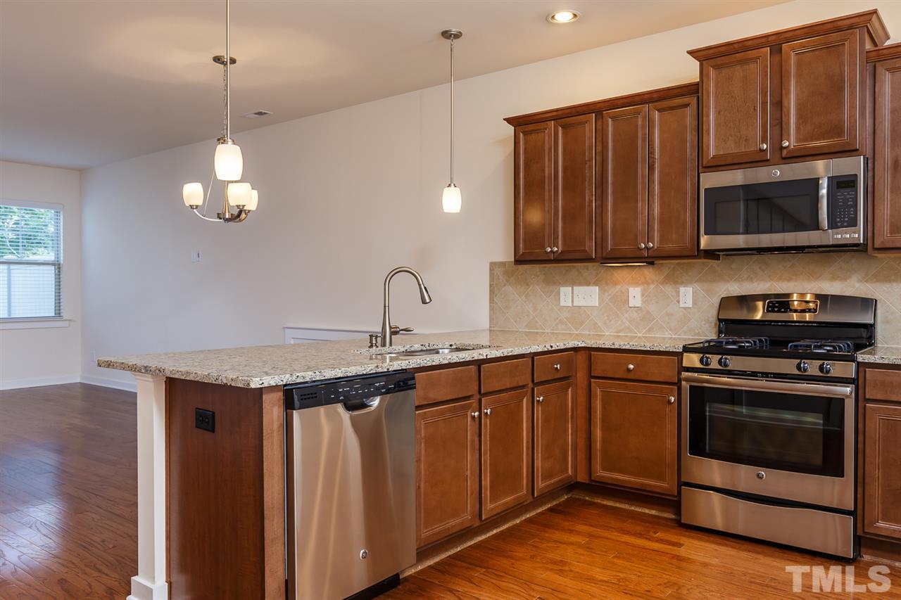 7841 Allscott Way Raleigh, NC 27612 - Photo 3 of 20 a kitchen with stainless steel appliances granite countertop a stove a sink and a microwave