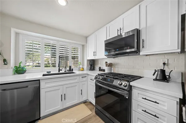 a kitchen with white cabinets and appliances